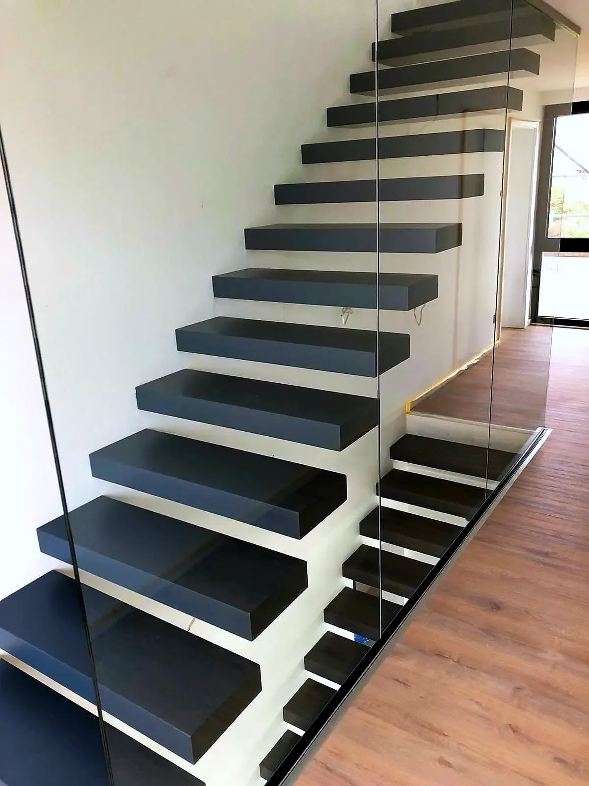 Kragarmtreppe – schwarze Stufen, Glasgeländer – Projekt von Treppen Sonsala