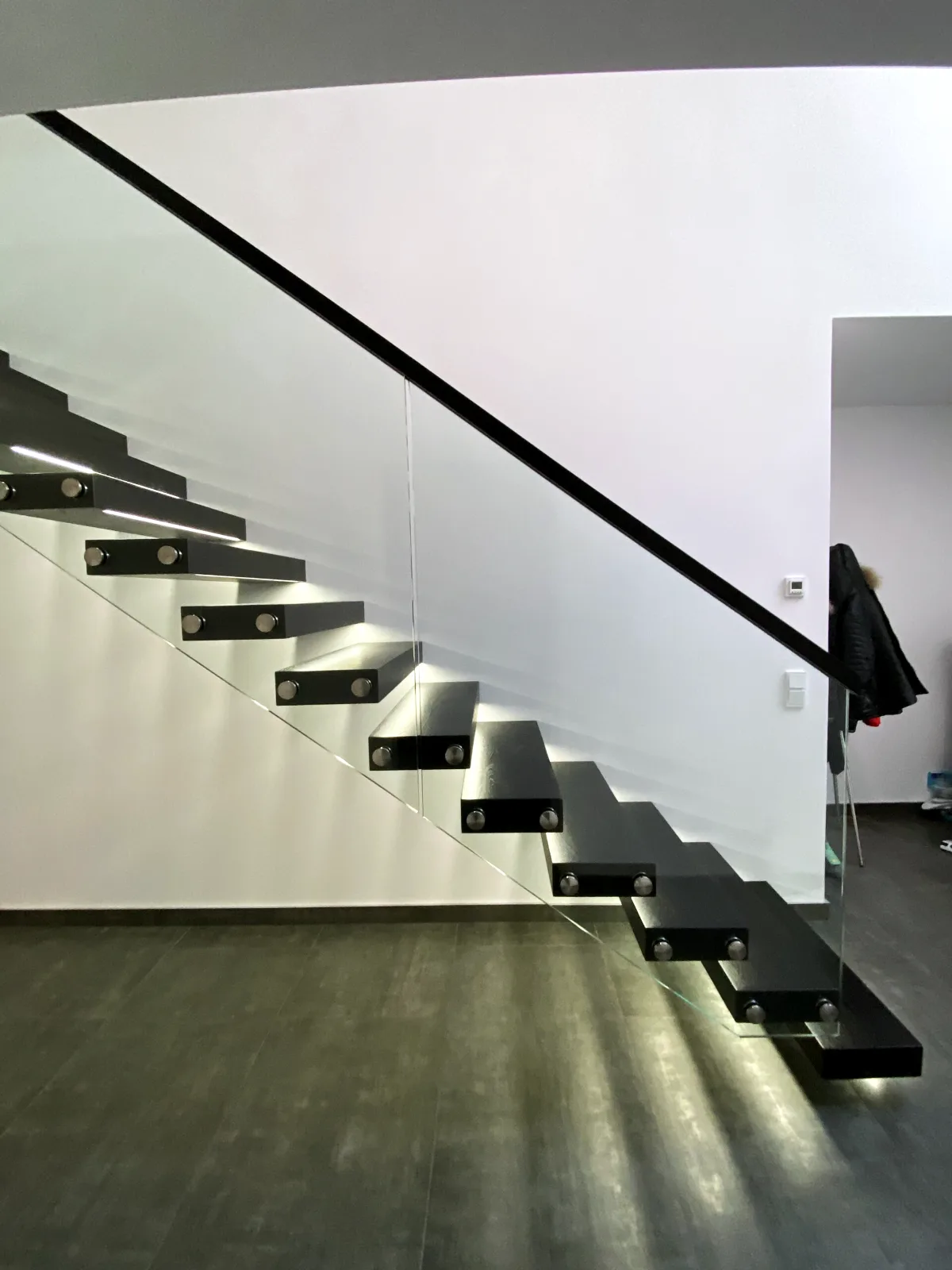 Kragarmtreppe – schwarze Stufen, Glasgeländer, LED-Stufenlicht – Projekt von Treppen Sonsala