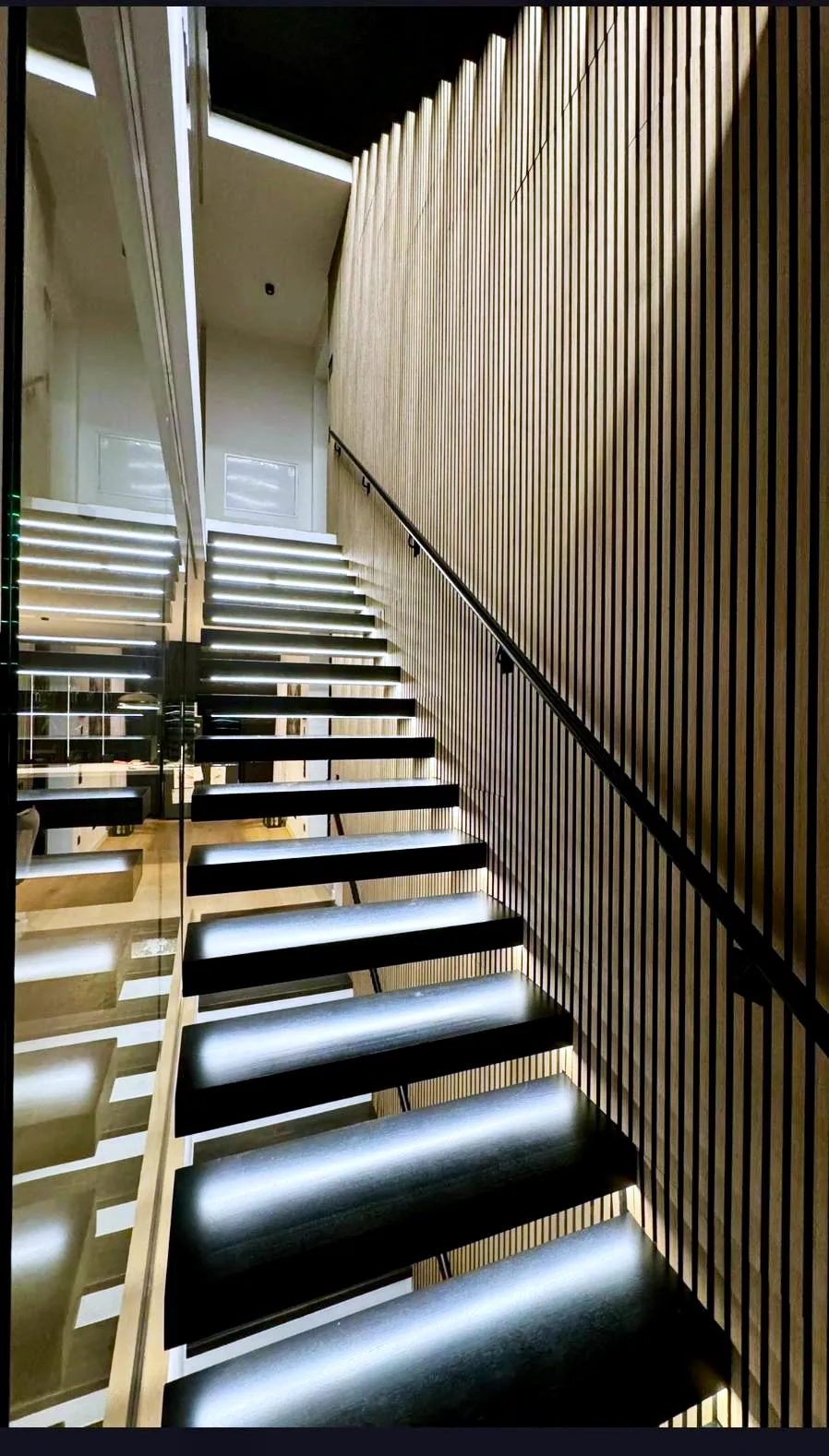 Kragarmtreppe – schwarze Stufen, ohne Geländer, LED-Stufenlicht, Handlauf an der Wand – Projekt von Treppen Sonsala